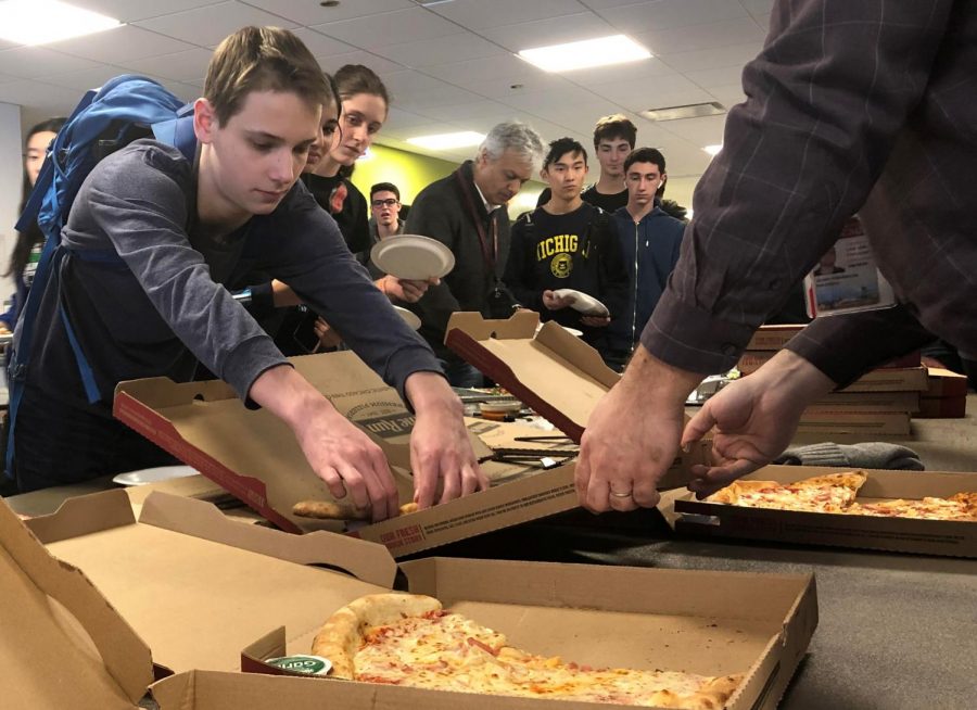 PILE OF PIES. Sophomore Addison Goolsbee reaches for a slice of cheese pizza during lunch in Café Lab Jan. 28. The line for the 180 Papa Johns pizzas and five salad plates provided by parents stretched into the hallway outside the cafeteria. Caption by Max Garfinkel.
