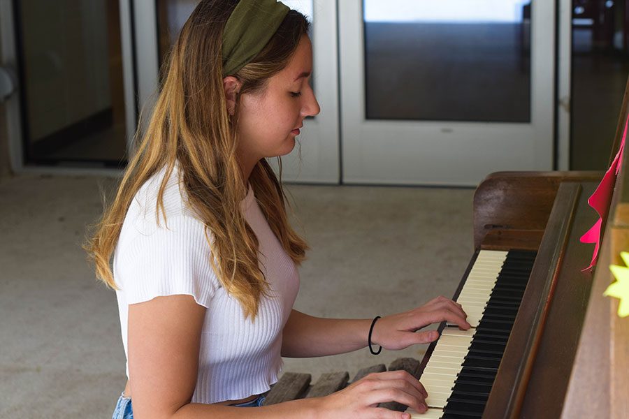 Ava McKula plays a song on the piano outside C116 near Judd Lobby.