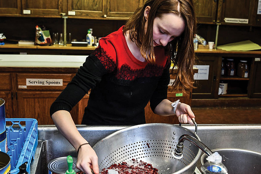 WASHING WITH CARE. Helping in her community on Dec. 8, sophomore Jane Barnard washes beans to make chili for the Hyde Park Food Pantry with the help of her family and members of her church. Through making chili, Jane has learned lessons about working in the kitchen and skills of collaboration. 
