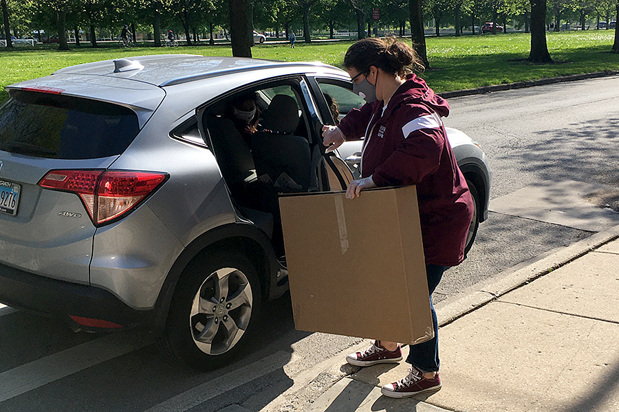 Dean of students Ana Campos places a box in Alia Thomas family car.