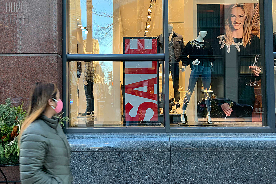 A shopper walks along Chicago’s North Michigan Avenue past a sign for a Black Friday sale.