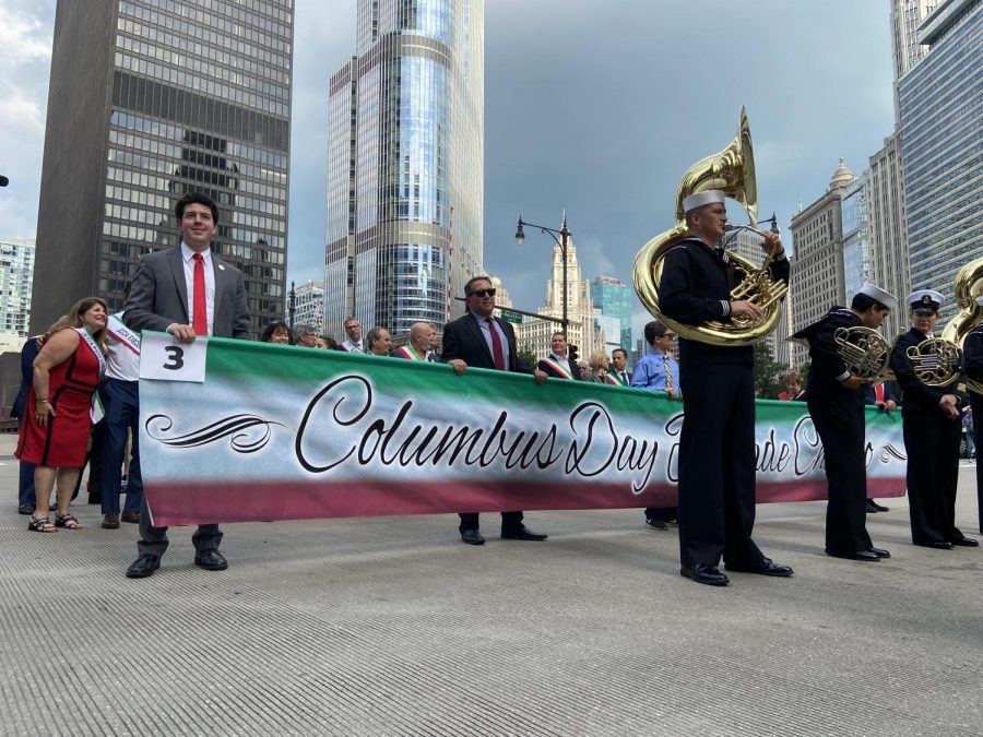 Organizers hold up the “Columbus Day Parade” sign at the corner of State Street and Wacker Boulevard at the beginning of the parade route on Monday, Oct. 11. The organizers were preceded by a marching band.