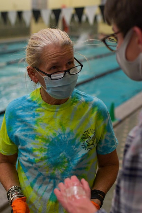 Swim coach Kate Chronic addresses senior Spencer McKula after she applies a bandage to his hand injury. Using first-aid skills she gained while working as a paramedic, she removed Spencer’s stitches at swim practice. 