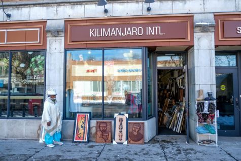 The owner of Kilimanjaro International, Mother Rose, stands by the art she displays outside the store.