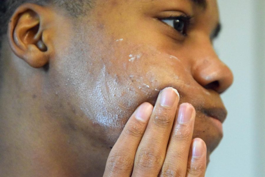 Junior Blake Dunkley applies a cream to his face. Many male students utilize skin care routines, but they find that products are not marketed well toward a male audience.