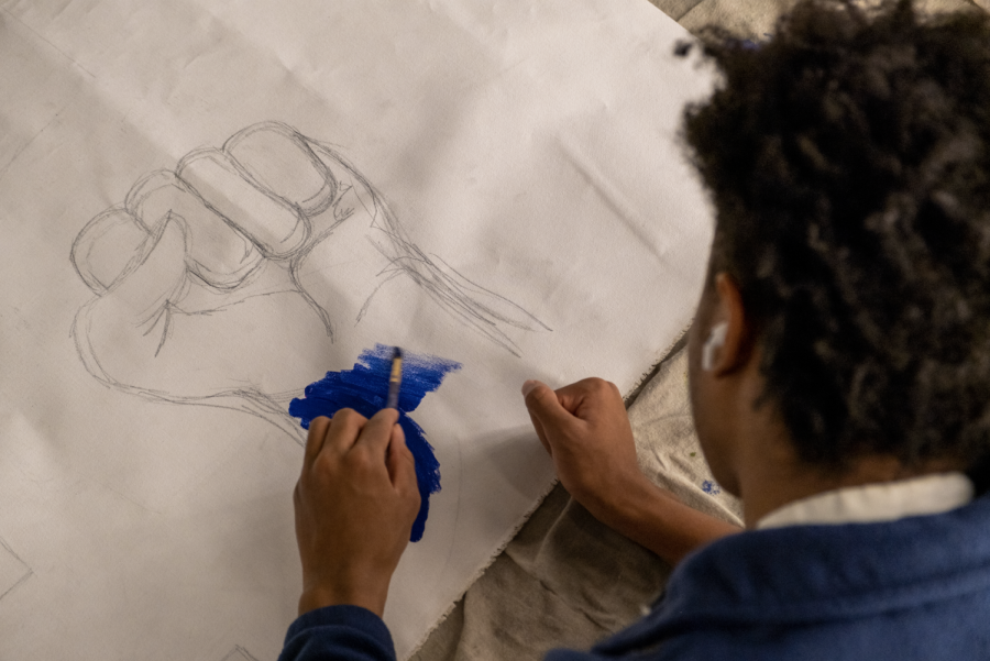 At the mural painting workshop, Sophomore Brandon Jones fills in part of the BRAVE logo with blue.