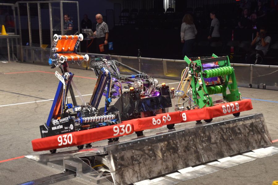 The Cache Money 8096 robot (center) works with their alliance to attempt a triple balance on the charging station during the second playoffs/eliminations match at the Wisconsin regional.
