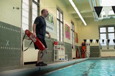 U-High P.E. teacher Daniel Dyra stands at the edge of a pool coaching students. The lifeguarding unit is now offered to U-High students after a hiatus during the pandemic, in which students can obtain American Red Cross certification.