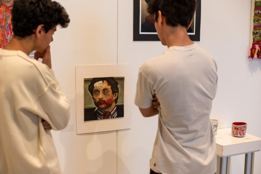 Two students examine a piece on display at the senior show in the Corvus Gallery. The show will run until May 13 and is a display of many types of art.