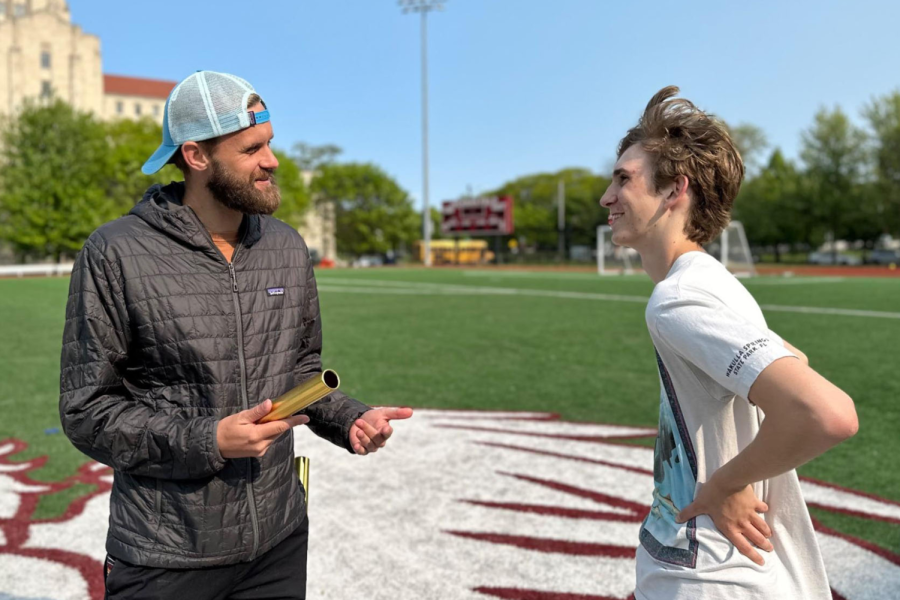 PASS IT ON. Austin Warner talks to runner Ellis Domenick about proper form to hand off the baton on Jackman Field on May 17. Mr. Warner is preparing his athletes for the state meet May 25-27.