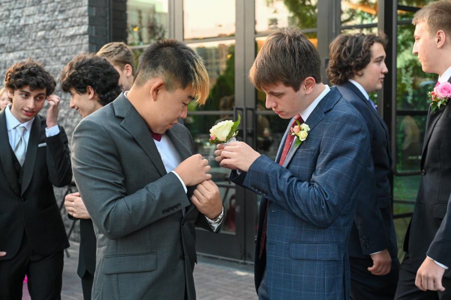 Senior Cristian Ferreyra helps senior Vincent Zhang pin his boutonniere to his jacket.