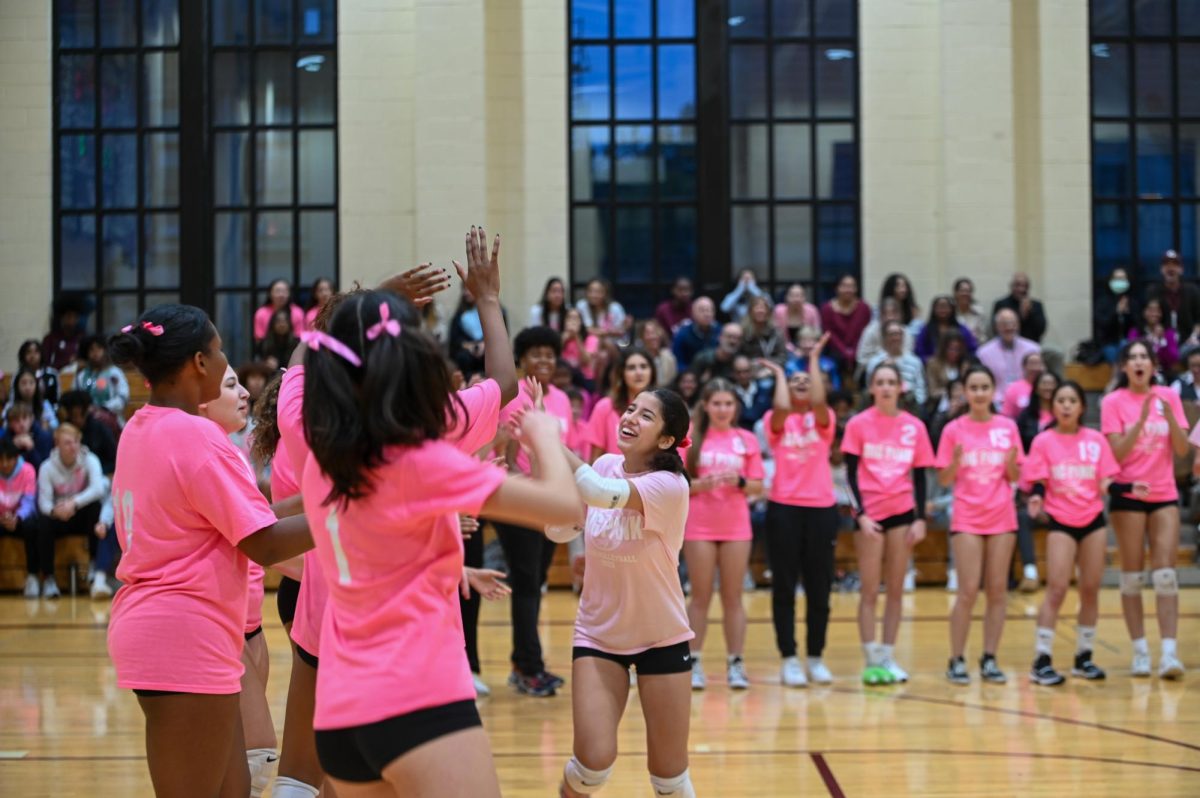 Running across the court, captain Satana Romero, a senior libero, is high-fived by her cheering teammates as a part of their pre-game tradition.