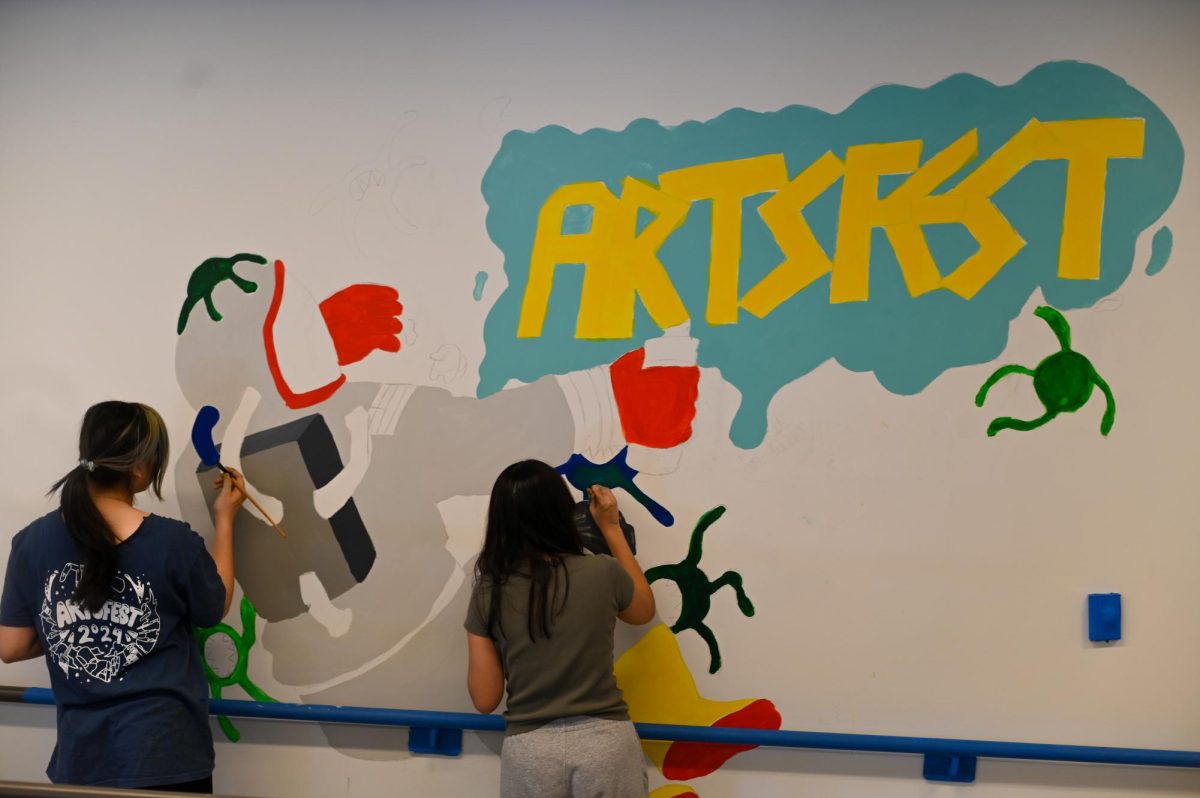 Juniors Ace Ma and Dilara Dogan paint the ArtsFest 2024 mural on the third floor of Belfield Hall. They worked with Lisa Tao and Sebastian Gans, spending their day working on their mural. “It was a lot of fun,” Ace said. “When I start an art project, I really can’t stop until I’m finished. It was a group of people: Sebastian did the design really, really well. It was really fun to be able to work on something big all day. I like being able to work on projects non-stop.” 

