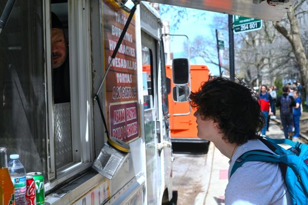 Sophomore Dominic Vaughan stands at a food truck, ready to order. Students say that the food trucks on South Ellis Avenue offer a vibrant environment of aromas, people and fresh foods.