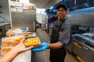 Café Lab worker Mike Ligon hands over a freshly-made serving of curly fries to a student. Lab has partnered with a new food vendor, HandCut Foods for the 2024-25 school year and on.