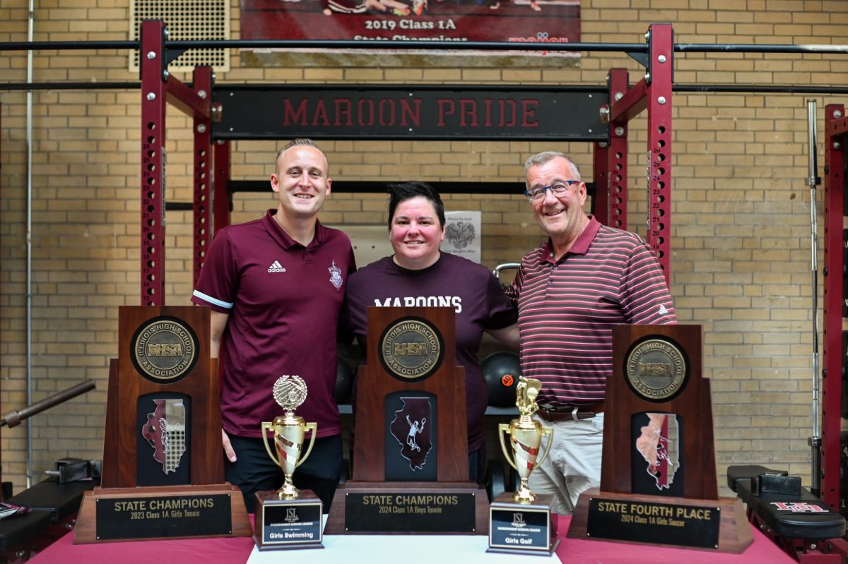 New athletic administrators, Josh Potter, Becky Chmielewski and David Ribbens display recent U-High athletics awards in the fitness center.