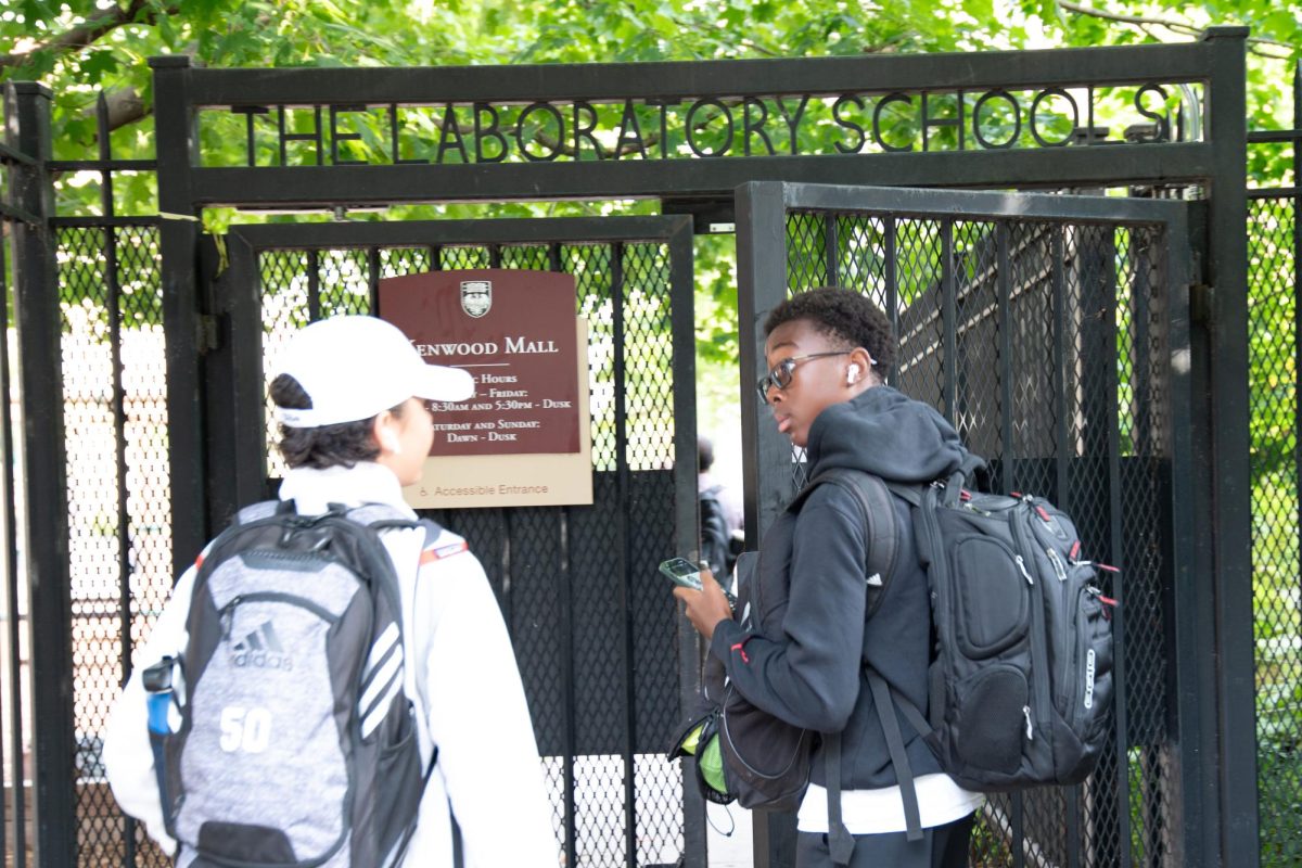 A student holds the Kenwood Mall gate open for a friend in the morning. The Laboratory Schools are implementing new security policies, including a new pre-screening policy for all visitors and providing after-hours Kenwood Mall access to parents.