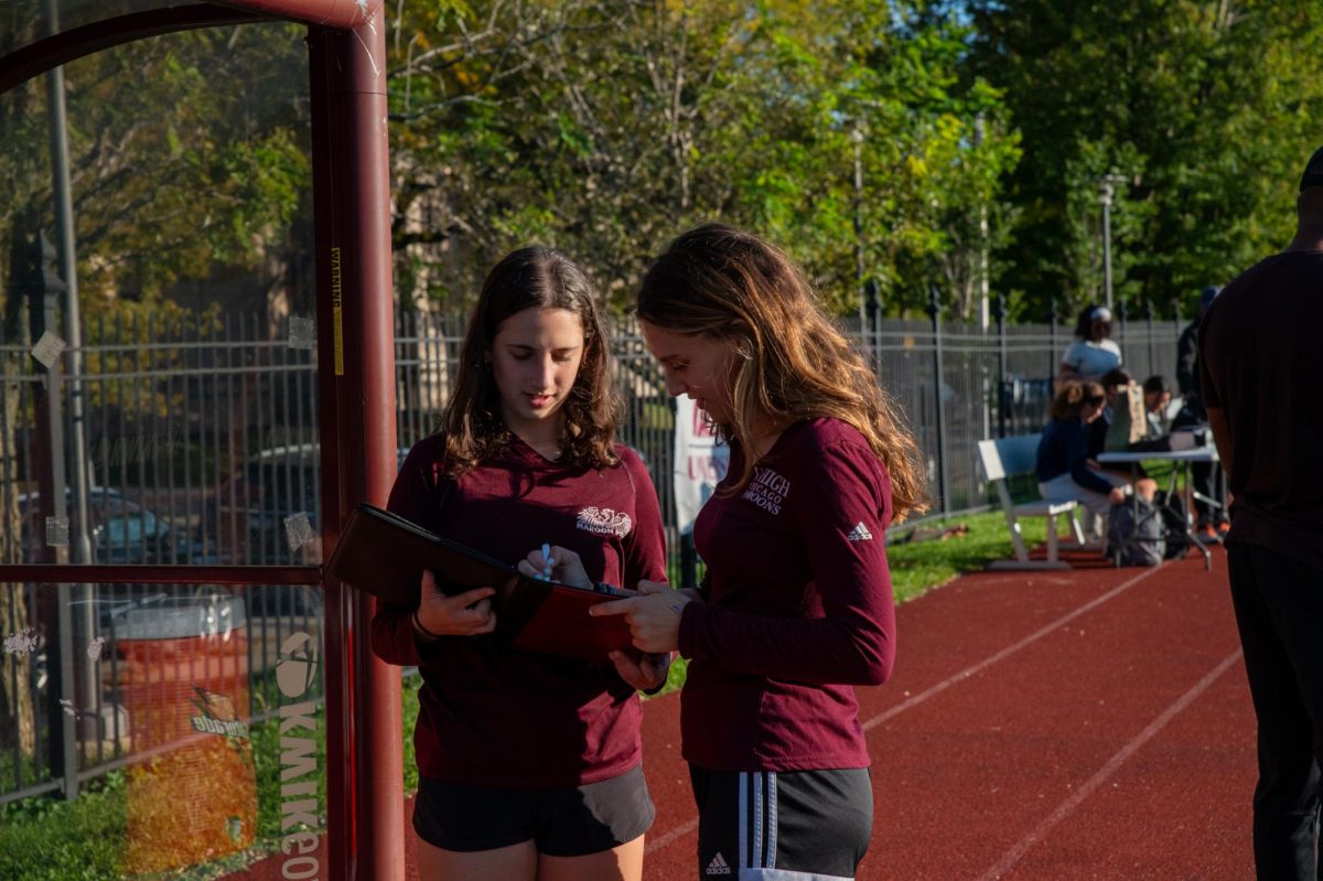 Seniors Lucy Aronson and Orly Eggener stand on Jackman Field, making substitutions for Lab’s seventh grade boys soccer team.