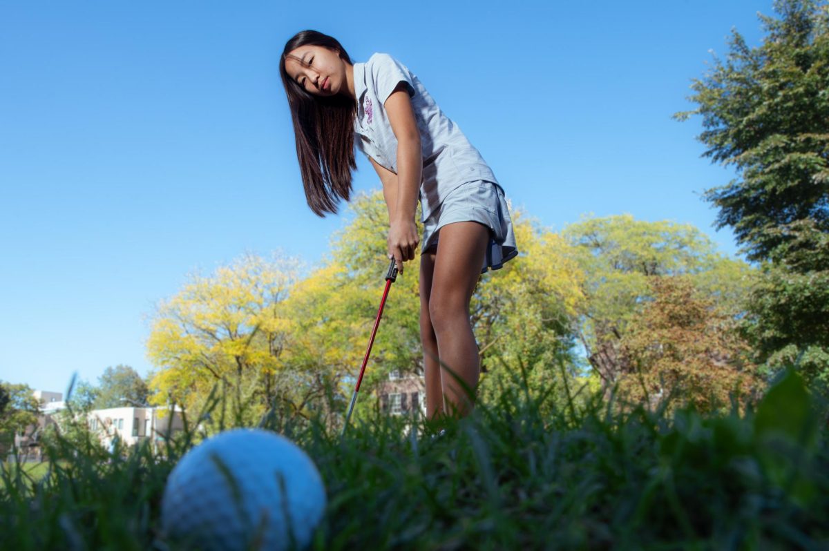 After putting, senior Amelia Tan watches the golf ball roll smoothly across the green.