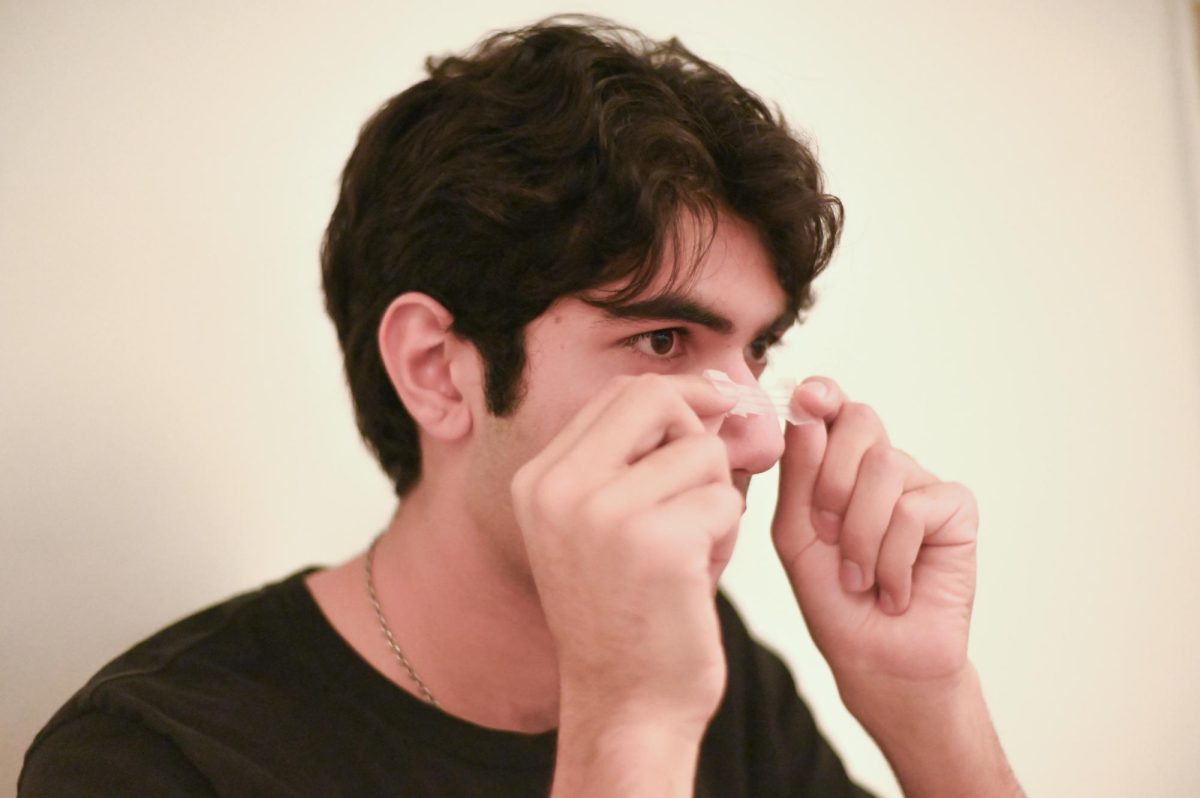 Stuffy to serene. Senior Nyel Khan applies a breathing strip across his nose. Many athletes from NFL Hall of Famer Jerry Rice to high school soccer players have used breathing strips to enhance airflow during competition.