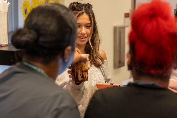 Sophomore Mira Reddy receives her drink from baristas at Lab's coffee shop, The Grind. Students frequent The Grind throughout the day, relying on it is not just a place to grab a snack but a source of beverages that get them through the school day.