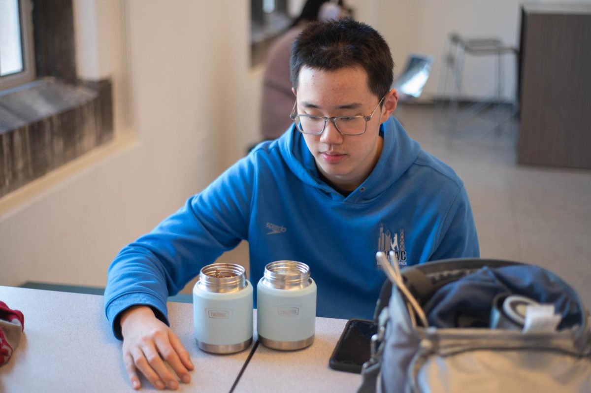 HOMEMADE COMFORT. Senior Jeffrey Wang prepares to eat the food his mother packed for lunch. Packing lunch has been linked to healthier eating habits, as homemade meals often contain less processed food and lower sodium levels than cafeteria or restaurant meals.