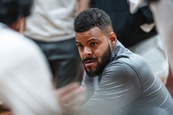 TRIUMPHANT TACTICS. Surrounded by players, varsity boys basketball coach Andre Battle discusses mid-game adjustments during a game against the Latin School of Chicago in Upper Kovler Gymnasium on Jan. 17. The game ended in a decisive 58-44 victory.
