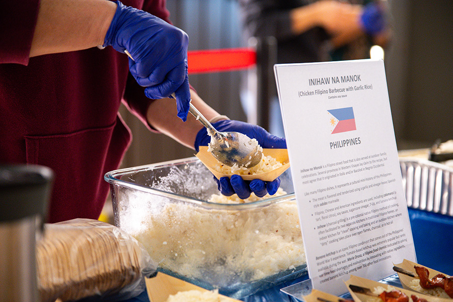 FILIPINO FLAVORS. A volunteer spoons inihaw na manok, a Filipino street food with rice. During the annual International Day lunch, various cultural foods were brought and provided by parent volunteers. Photo by Simon Vaang.