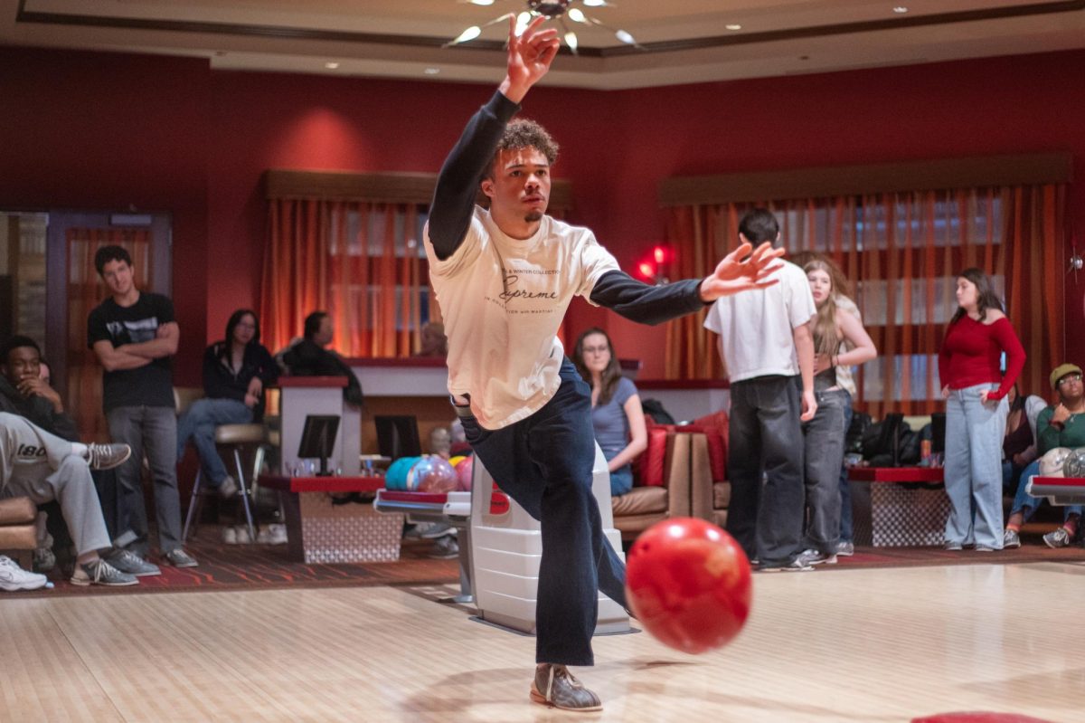 STRIKE A POSE. Staring down the bowling lane, Desmond Tarkowski-Pope L. delivers his bowling ball in hopes of earning a strike or spare. Ahead of the retreat, seniors ranked which activities they wanted to participate in, and bowling served as an alternative for those who did not want to ski. Photo by Lucy Byrnes.