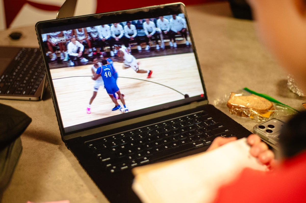 GAME ON. A student watches college basketball looking to improve his technique. U-High athletes have watched sports to give them inspiration to improve their own skills.