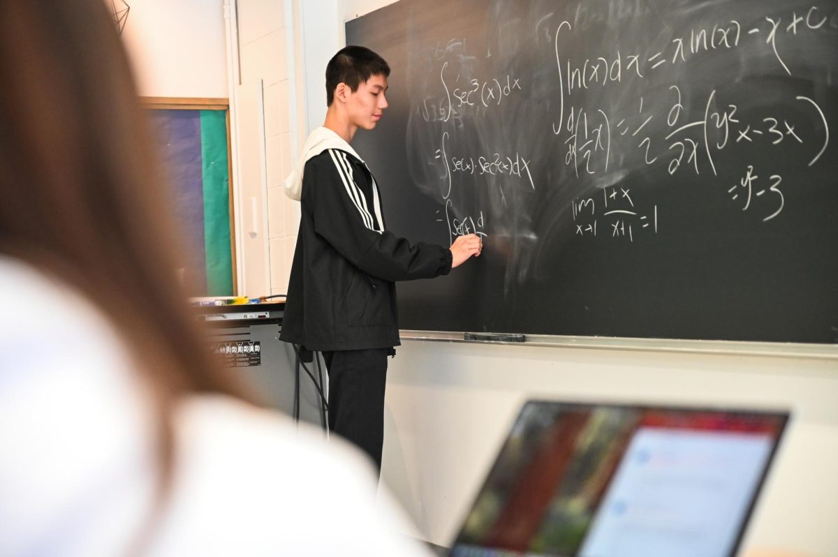 Junior Tinson Xu writes equations on a chalkboard during a math team practice earlier this year. The team had various top individual results and placed second overall in the state. 