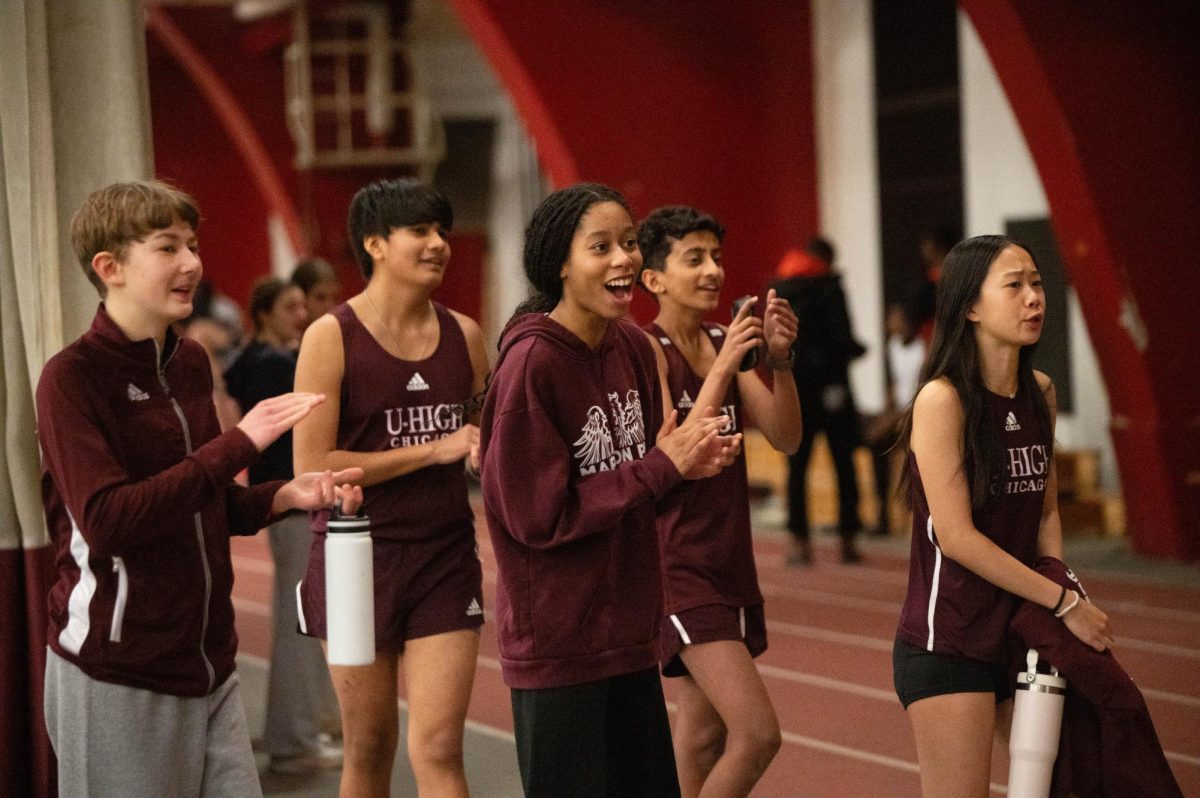 CROWD CLAPS. Ninth graders Otto Kallembach, Axel Lais, and Tanvir Singh, and sophomores Anya Shi and Morgan Purcell cheer along their teammates at an indoor track meet on Feb. 6 at Henry Crown Field House.