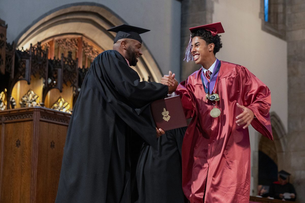 DIPLOMA DAP-UP. Receiving his diploma while draped in medals, senior Ty Quiles high-fives principal Martin Woods. 
