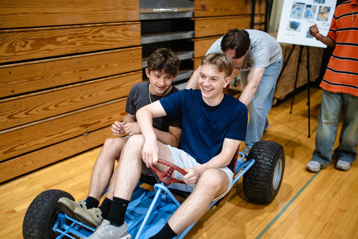 GO-KART GO! Senior Dennis Oskan pushes juniors Jonas Hatcher, left, and Ian Bennert, right, in a go-kart as a part of May project presentations. The go-karts were a part of Dennis, Osvaldo Carterro, Sean Niro’s May Project, where the group bought parts and assembled the karts themselves.