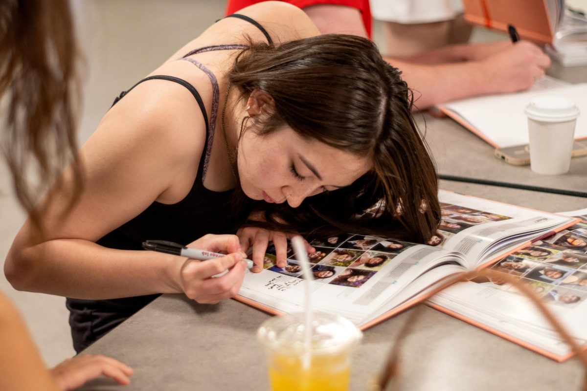 SENIOR SIGNING. Lydia Gilbert signs a friend’s yearbook. Seniors were given their yearbooks on the morning of June 4 during a breakfast event, and the rest of the school community received it during advisory the next day. 